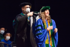 Laura Artim is hooded by Alan J. Lesse, MD.