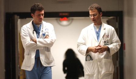 Two medical residents walking down a hospital corridor. 