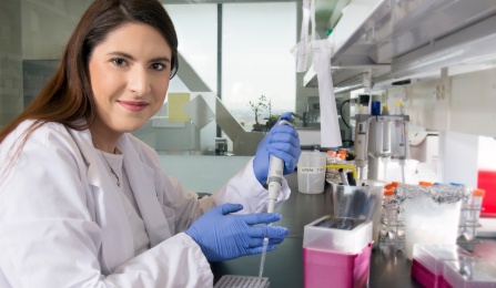 A student researcher examines liquid in a flask.