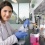 A student researcher examines liquid in a flask.