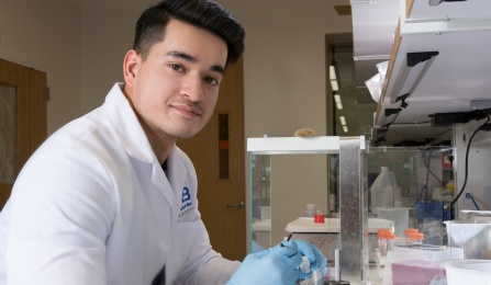Student examines a microscope slide in a research lab