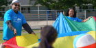 Faculty coach Mohammed Hamid, MD, and student volunteering with children on Day of Service, playing with a large parachute.