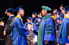 Andrew Hurst, who received dual degrees in biomedical sciences and psychology, is congratulated by Michael E. Cain, MD, medical school dean.