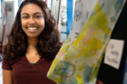 First-year medical student Tricia Mathew poses next to a scarf she painted in a Jacobs Arts and Visual Interest Society silk painting workshop.