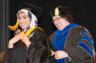 Master’s graduate Maha Ali is hooded by Lee Ann Garrett-Sinha, PhD, associate professor of biochemistry.