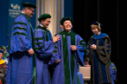 Minje Ha is overcome with emotion as he is hooded by his brother, Jay (Jewook) Ha. Looking on at far left is Thomas C. Mahl, MD. At far right, is Suzanne G. Laychock, PhD.