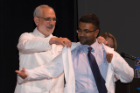 Alan J. Lesse, MD, left, helps Muhaimen Rahman into his white coat, a symbol of students’ commitment to professionalism and empathy.