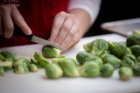 A student halves Brussels sprouts as part of a meal preparation exercise.
