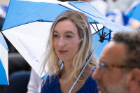 Haley M. Goodman, a trainee in the emergency medicine residency program, makes use of a blue-and-white UB umbrella that was handed out to all participants at the outdoor ceremony.