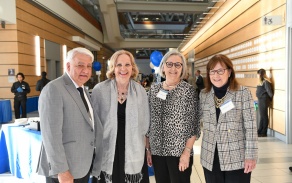 Four people standing at an alumni event in the atrium. 