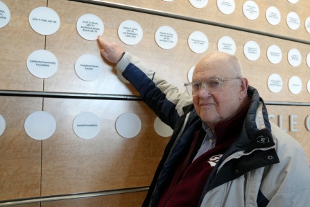 Scott Kirsch '71 pointing to his plaque on the atrium wall. 