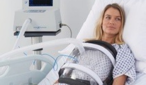 Adult with NPV sitting up in a hospital bed. 