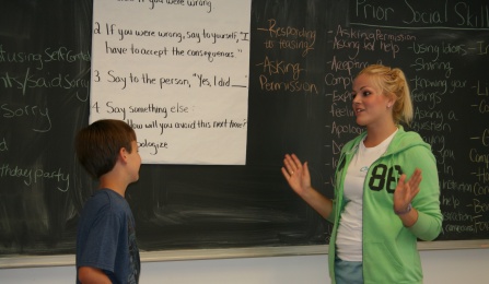 summerMAX teacher discusses their lesson in front of a chalkboard. 