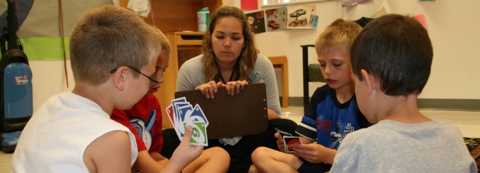 Children playing the card game Uno with an instructor. 