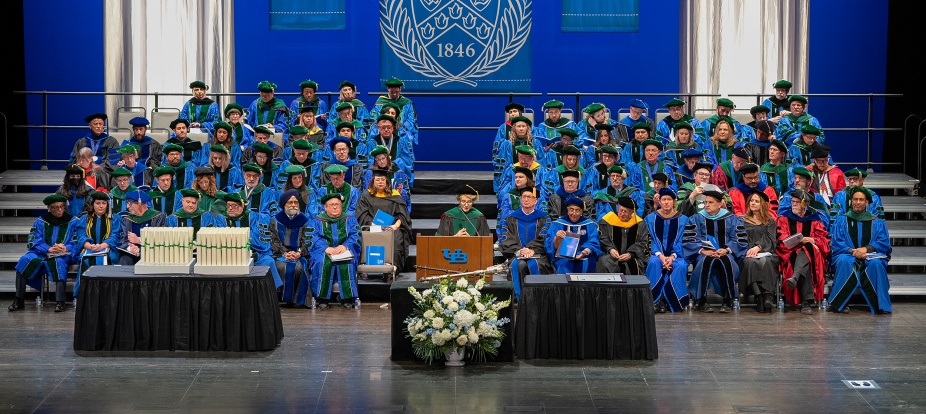 Faculty members are on stage at the commencement ceremony. 