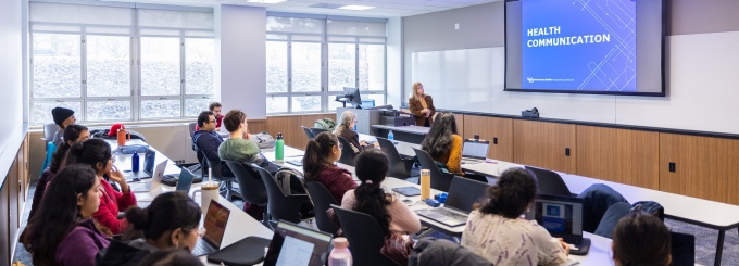 Classroom with students and professor looking at a presentation. 