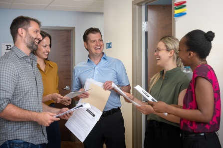 Group of residents and faculty standing in a hallway talking. 