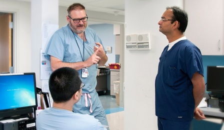 Faculty members conversing with a resident in a clinic.