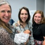 Group of women in a clinical setting holding a baby. 