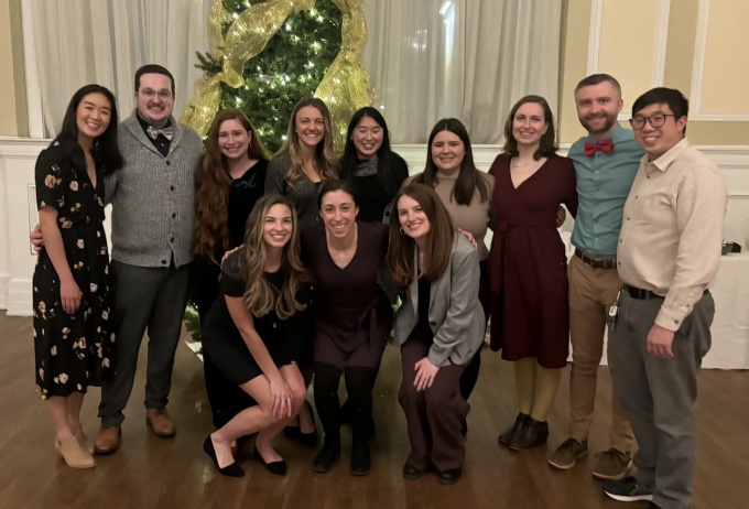 Residents standing in front of a decorated tree durig a holiday party.