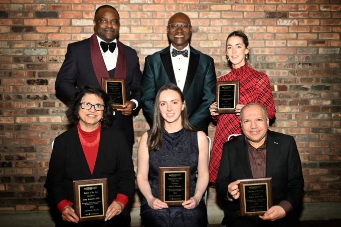 Past awardees holding their plaques during the holiday party.