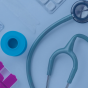 A stethoscope sits on a table with medications. 