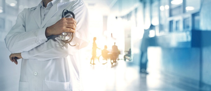 A physician stands in a clinical setting. 