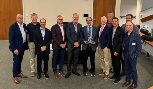 Faculty with Savoie holding an award.
