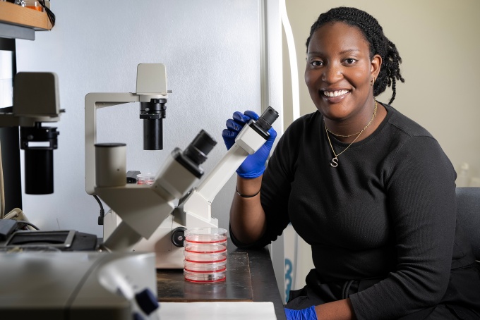 Sefunmi Babatunde sitting at a microscope. 