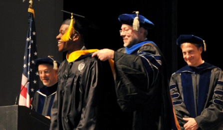 James R. Olson, PhD, hoods a new graduate at commencement. 