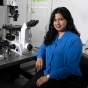 Niharika Jawalkar sitting near a microscope. 