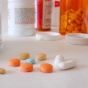 Various pills strewn across a white countertop. 