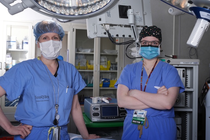 Two fellows with scrubs and masks on. 