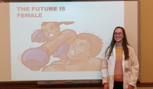Zoom image: Dr. Nicole Belko poses next to her debate-winning presentation. 