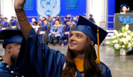 Student waving their hand at commencement.