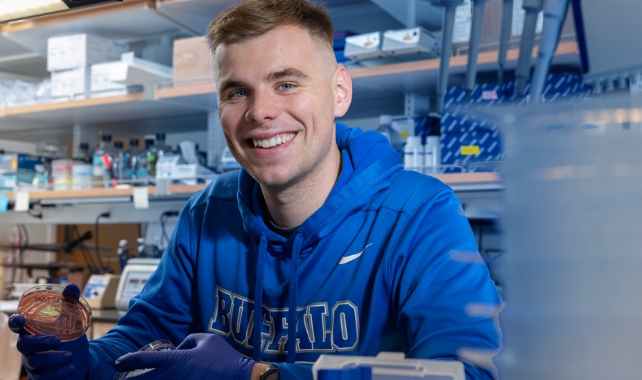 Student in research lab wearing UB sweatshirt.