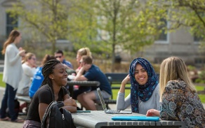 Students talking outside at a table.