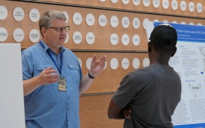 Faculty talking to a student in the Jacobs School atrium.