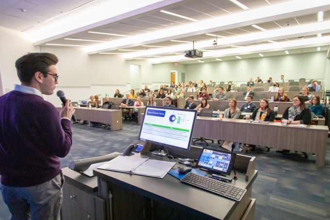 speaker giving a talk in a classroom to a group of students and faculty. 