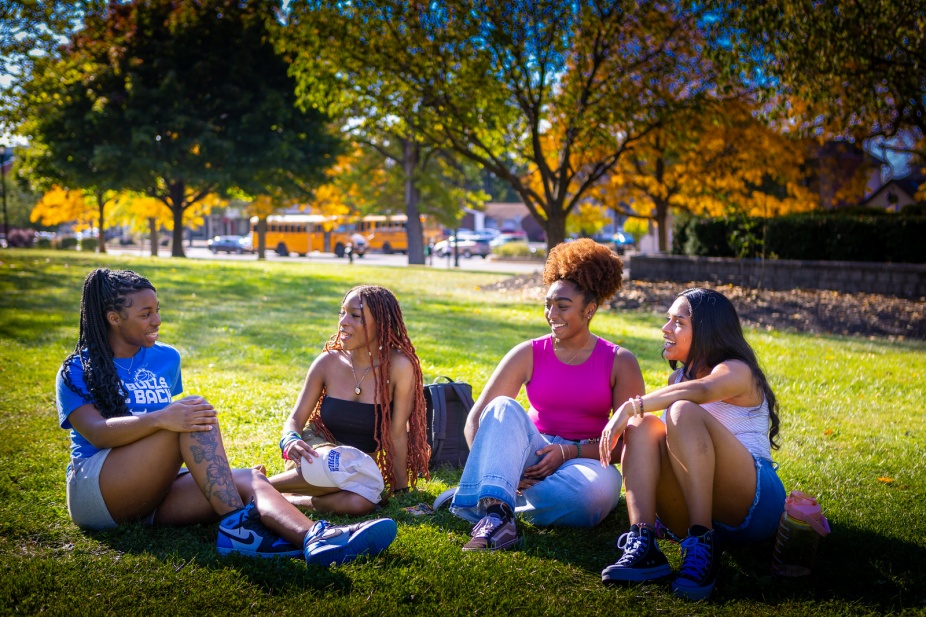 Students sitting on the lawn and talking on a sunny day.