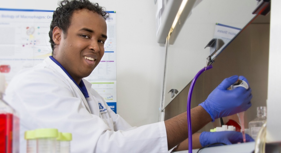 Undergraduate student working in lab and smiling.
