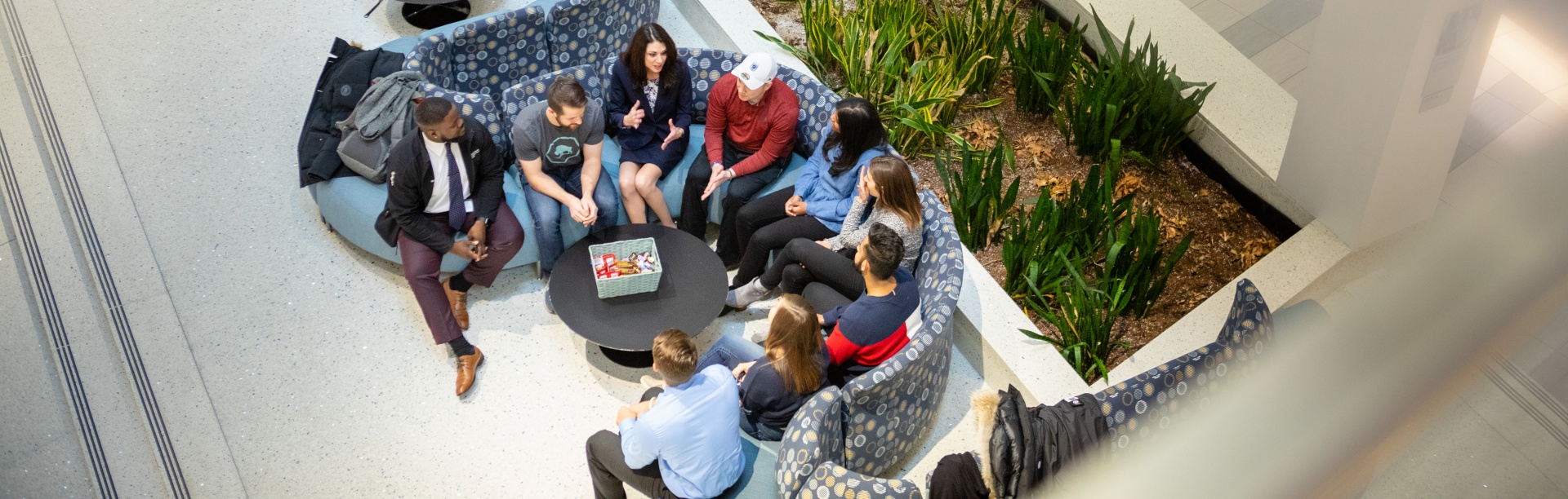 Students and professors sitting together on a couch within the Jacobs School of Medicine and Biomedical Sciences. 