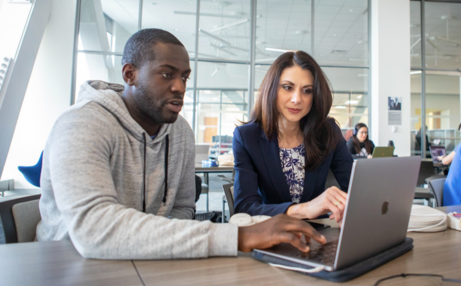 Dr. Meka, Director of the Medical Education and Educational Research Institute, assisting a student who is working on his laptop. 