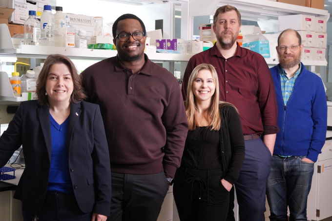 Five people standing in a lab setting. 