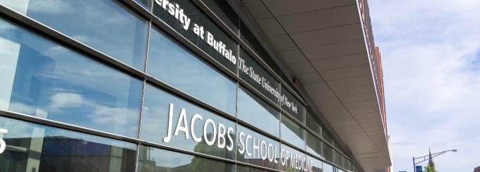 Jacobs School exterior with lettering that reads: University at Buffalo the State University of New York Jacobs School of Medicine and Biomedical Sciences.