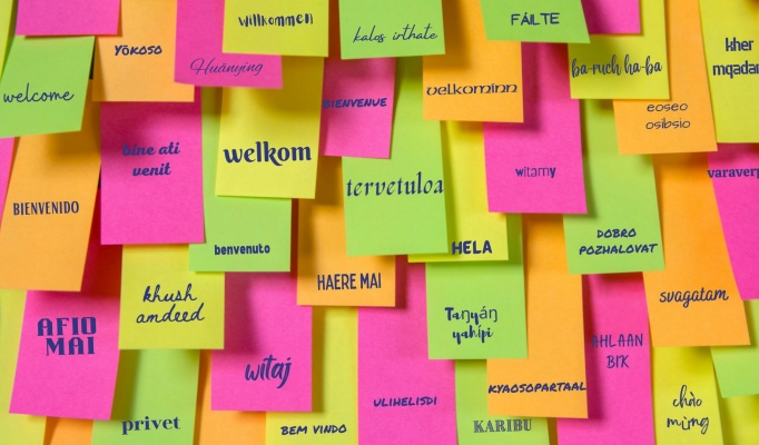 post it note wall with the word welcome in different languages. 