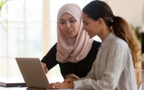 Two people sitting near a computer. 