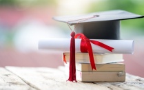 Stack of books with diploma and cap. 