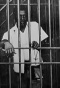 Black man inside of a jail cell. 