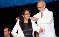 White Coat Ceremony. Young Female gets help putting the white coat by an older man. 